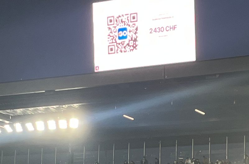 L'écran géant d'un stade de Super League affichant le compteur Live Wall du Papet du LS et son QR code (2 430 CHF en direct), au-dessus du virage Kop Sud.