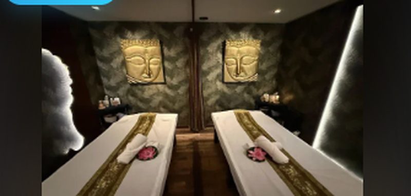 Salle d'institut GONG Paris — deux tables de massage côte à côte, ambiance feutrée tons or sur fond sombre, statues bouddha en arrière-plan.