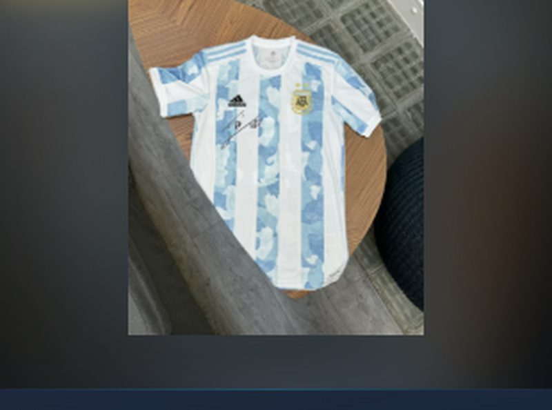 Maillot dédicacé par Messi — maillot officiel de l'équipe d'Argentine 2021, taille XS, floqué et signé à la main par Lionel Messi, présenté à plat sur parquet.